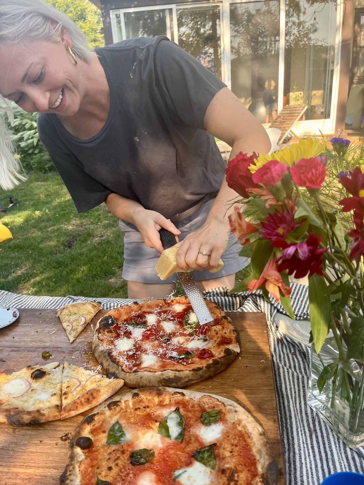 Grating parmesan onto a fresh pizza